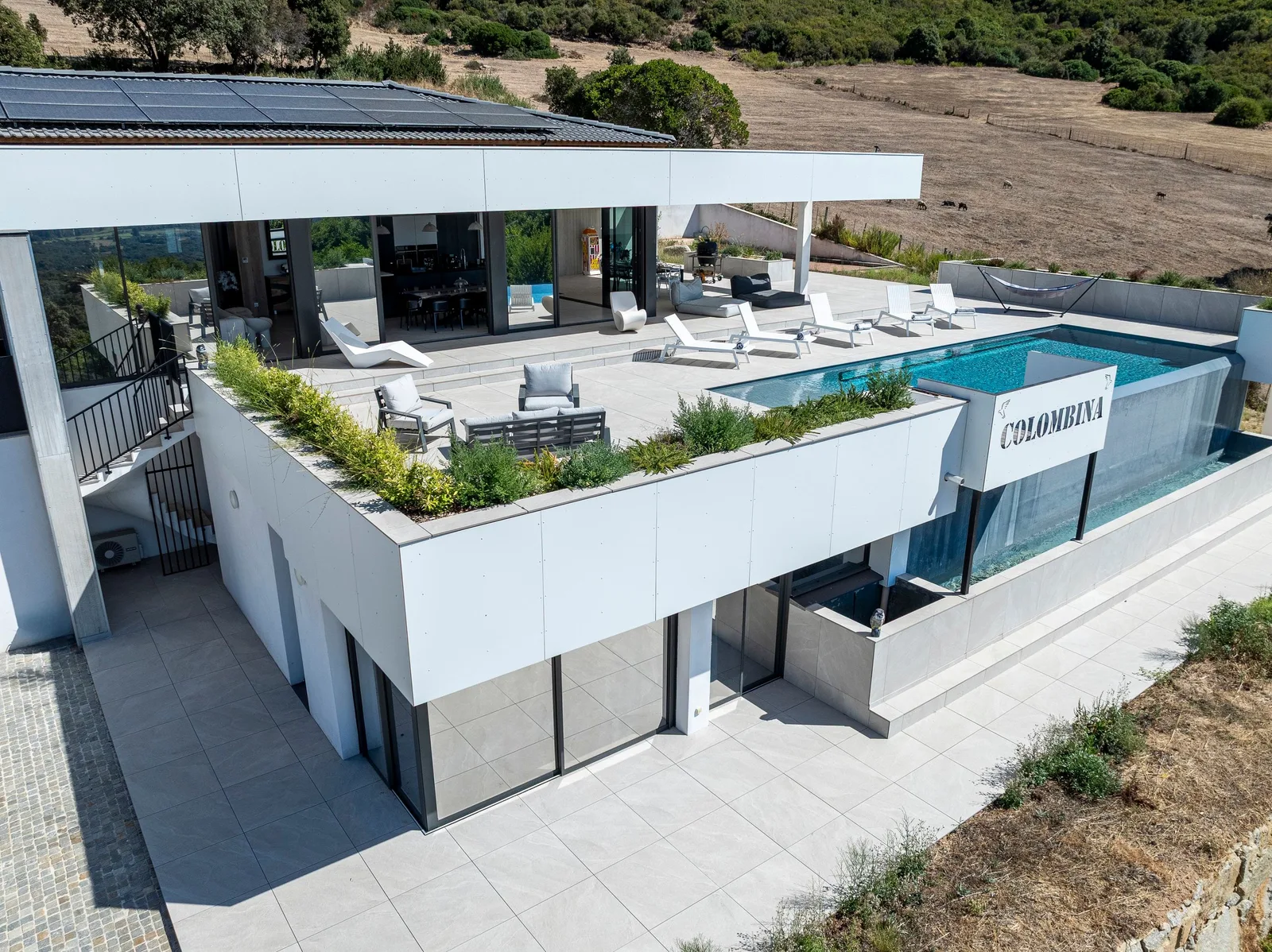 Vue plongeante sur les deux niveaux de la villa, terrasse végétalisée et garage en contrebas