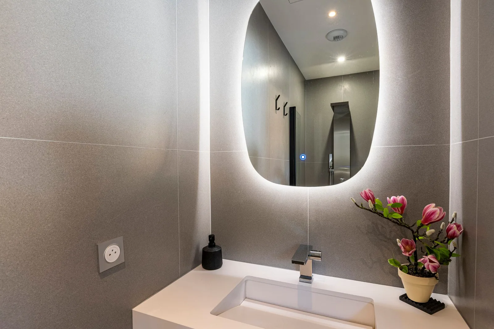 Salle de bain taupe, plan vasque blanc, miroir rétroéclairé et branche de magnolia