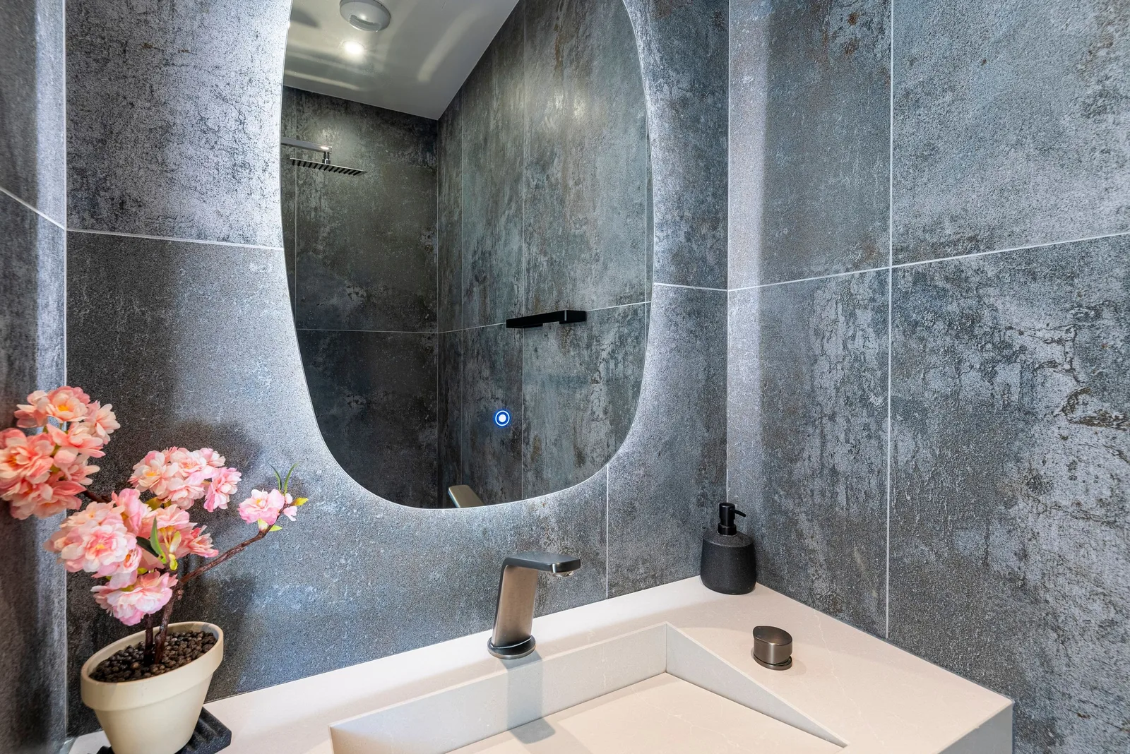 Salle d'eau en béton ciré gris, miroir organique rétroéclairé et douche à l'italienne