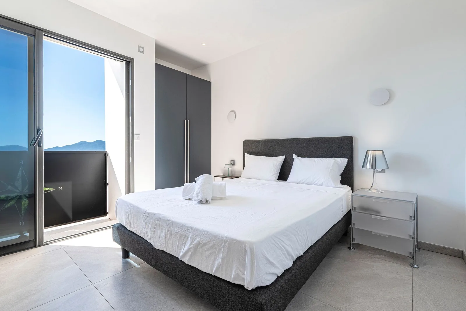 Chambre avec lit double et baie vitrée ouvrant sur la terrasse, vue sur les montagnes