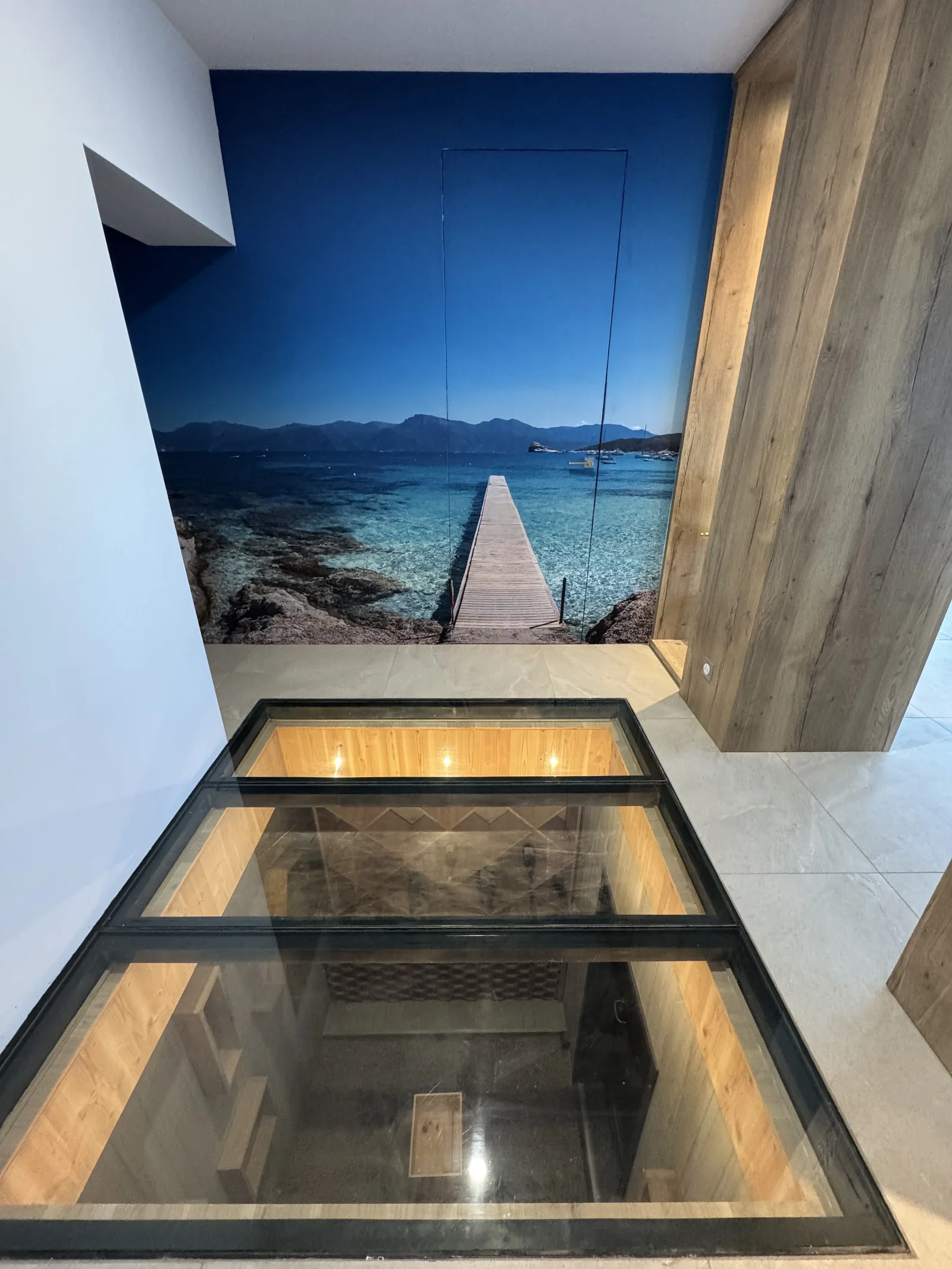 Cave à vin visible sous un plancher vitré, à l'entrée de la maison