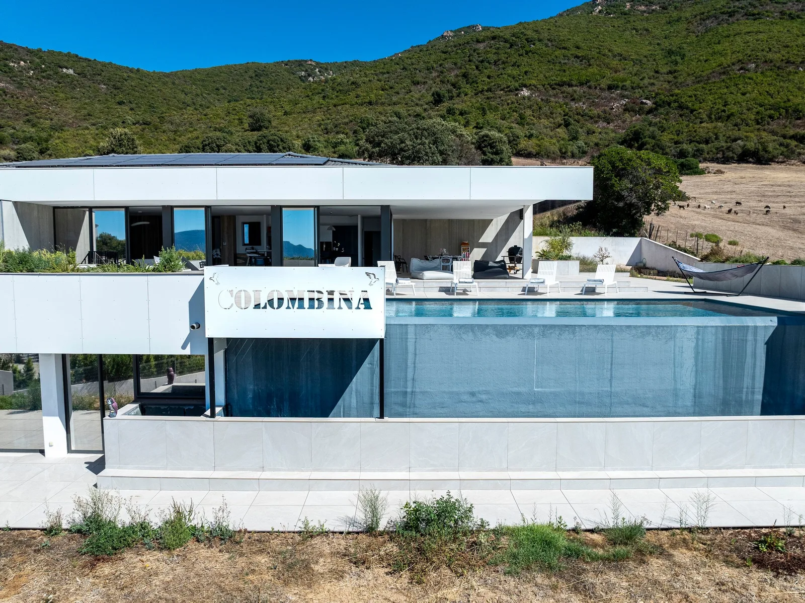 Enseigne Colombina sur le bassin à débordement, façade vitrée et maquis en arrière-plan