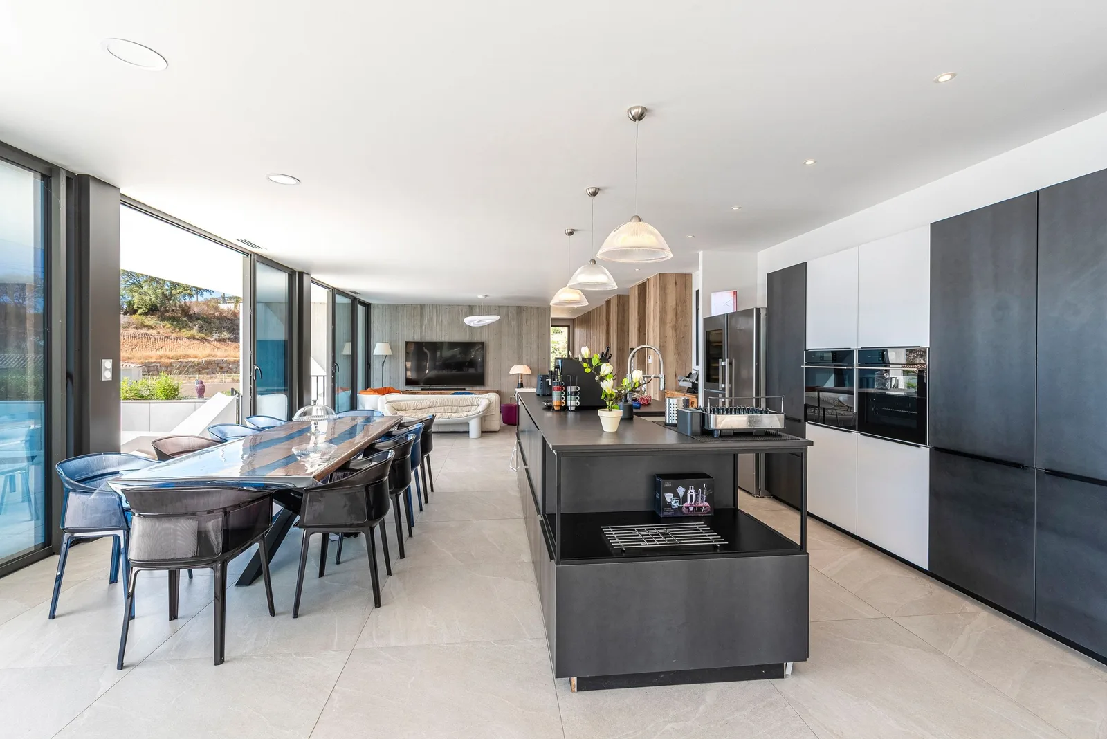 Enfilade cuisine et salle à manger, îlot anthracite, colonnes de rangement et baies vitrées