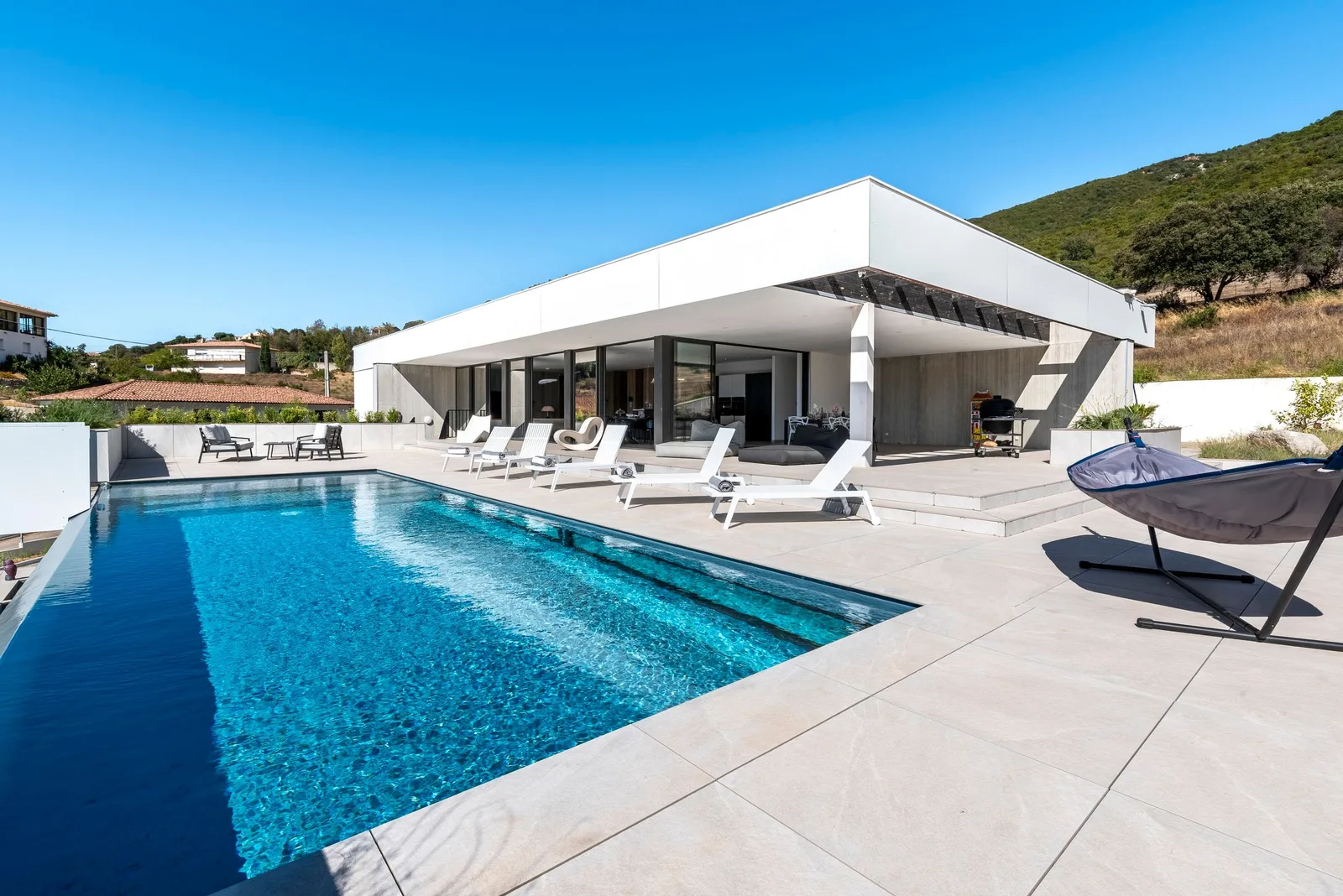 Piscine et fauteuil suspendu sous un olivier, vue sur les collines du golfe d'Ajaccio