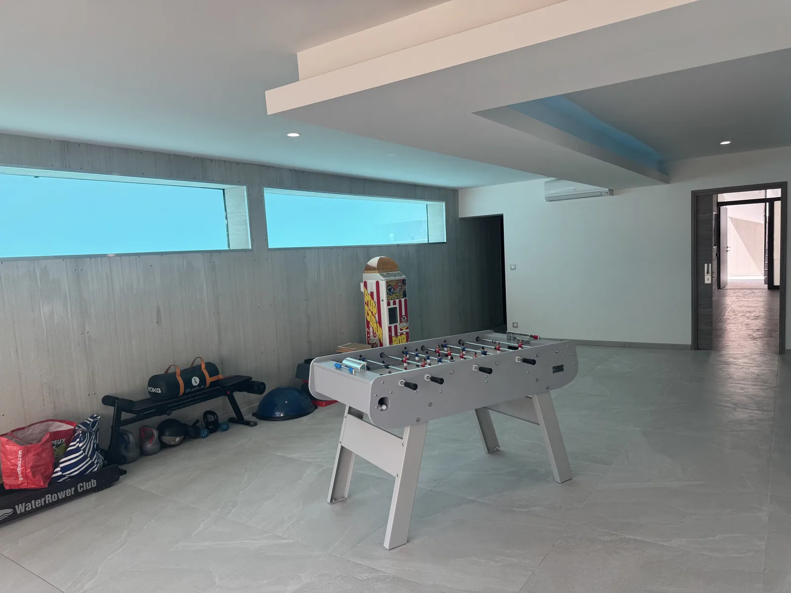 Baby-foot, rameur et kettlebells dans la salle de jeux aux murs de béton banché