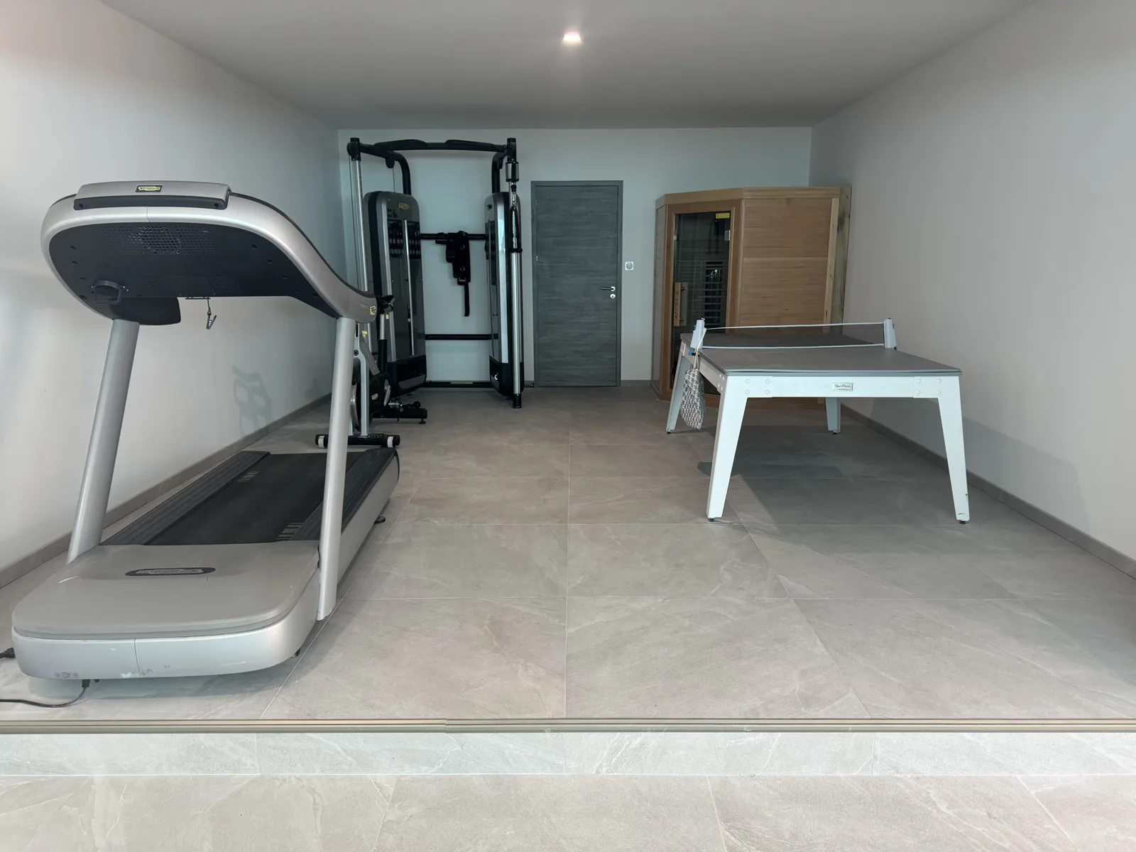 Salle de sport de la villa : tapis de course, station de musculation, sauna en cabine bois et table de ping-pong