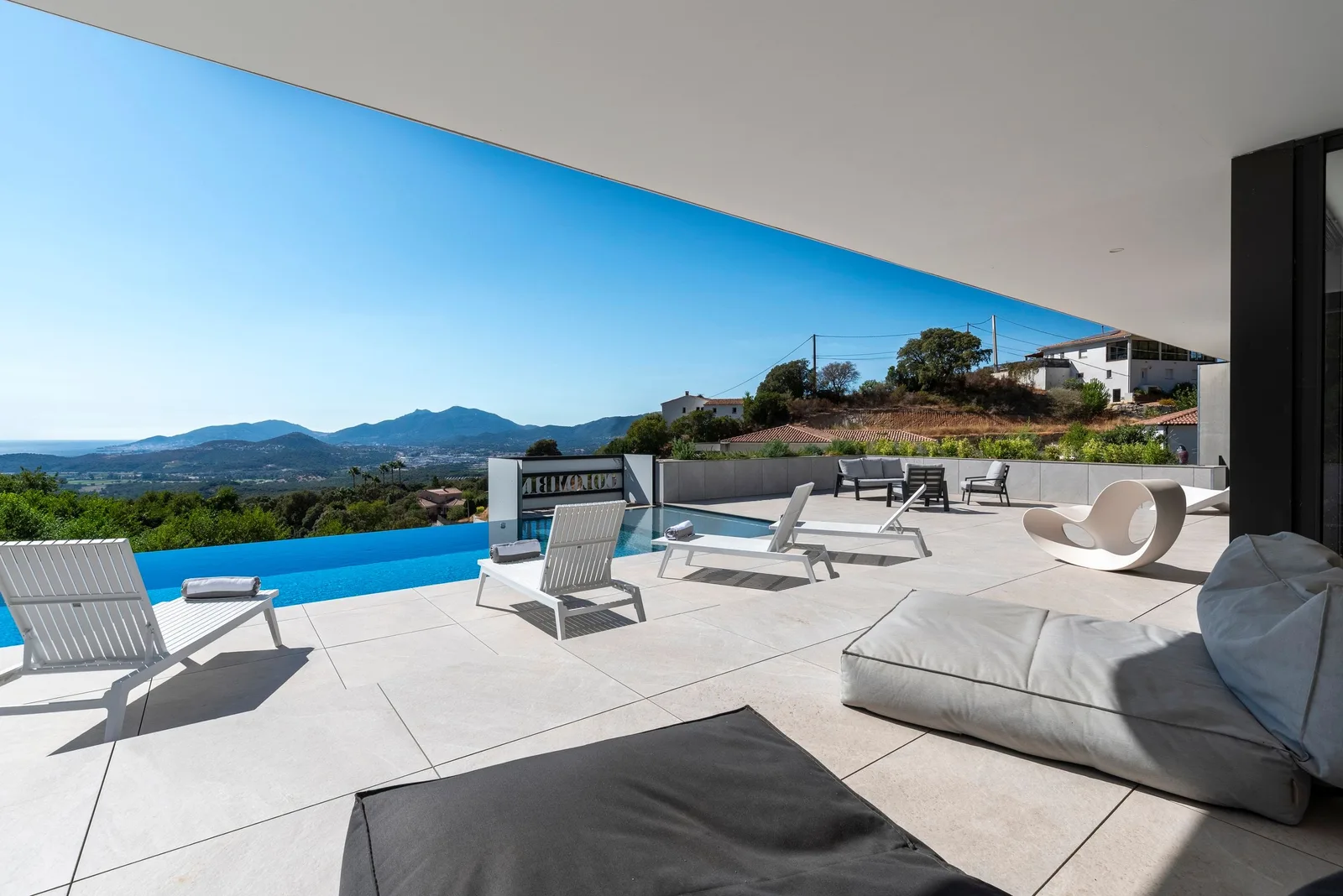 Terrasse couverte avec bains de soleil et transats, panorama sur les collines et la mer