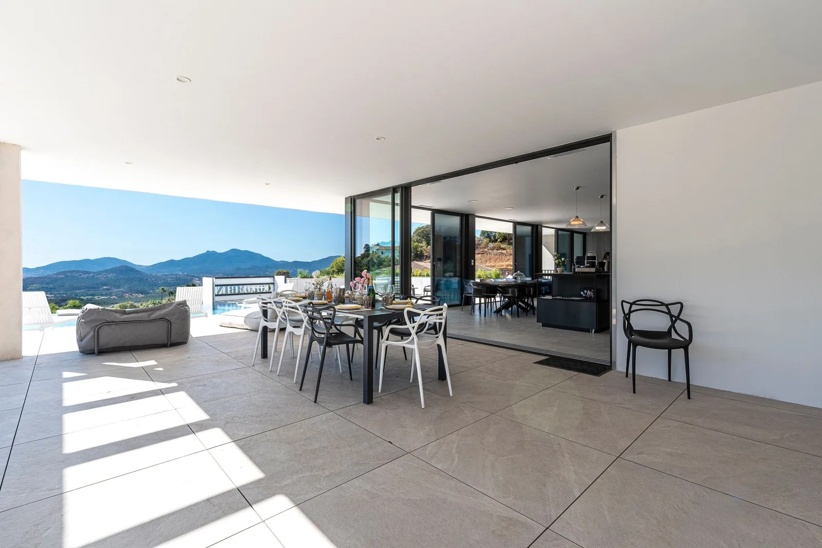 Terrasse couverte ouvrant sur le salon par les baies coulissantes, table et chaises design
