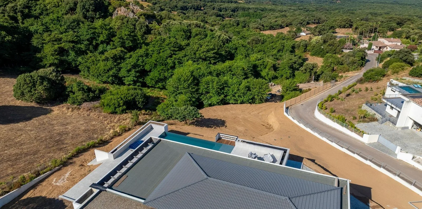 Vue aérienne de la villa à toit-terrasse et piscine à débordement nichée dans le maquis