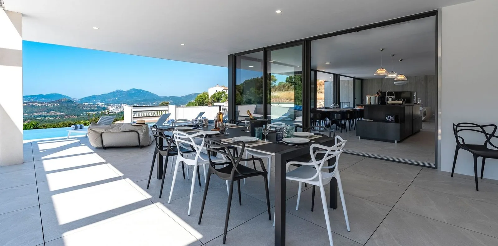 Terrasse couverte avec grande table à manger, chaises design et panorama sur le golfe d'Ajaccio
