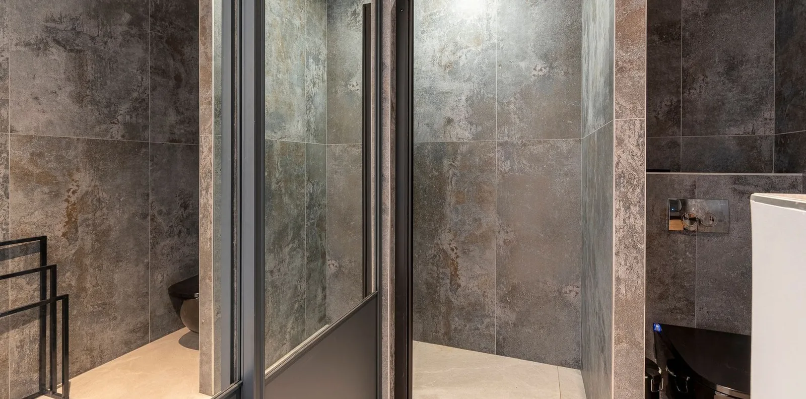 Salle de bain aux carreaux de pierre grise avec douche vitrée et WC suspendu