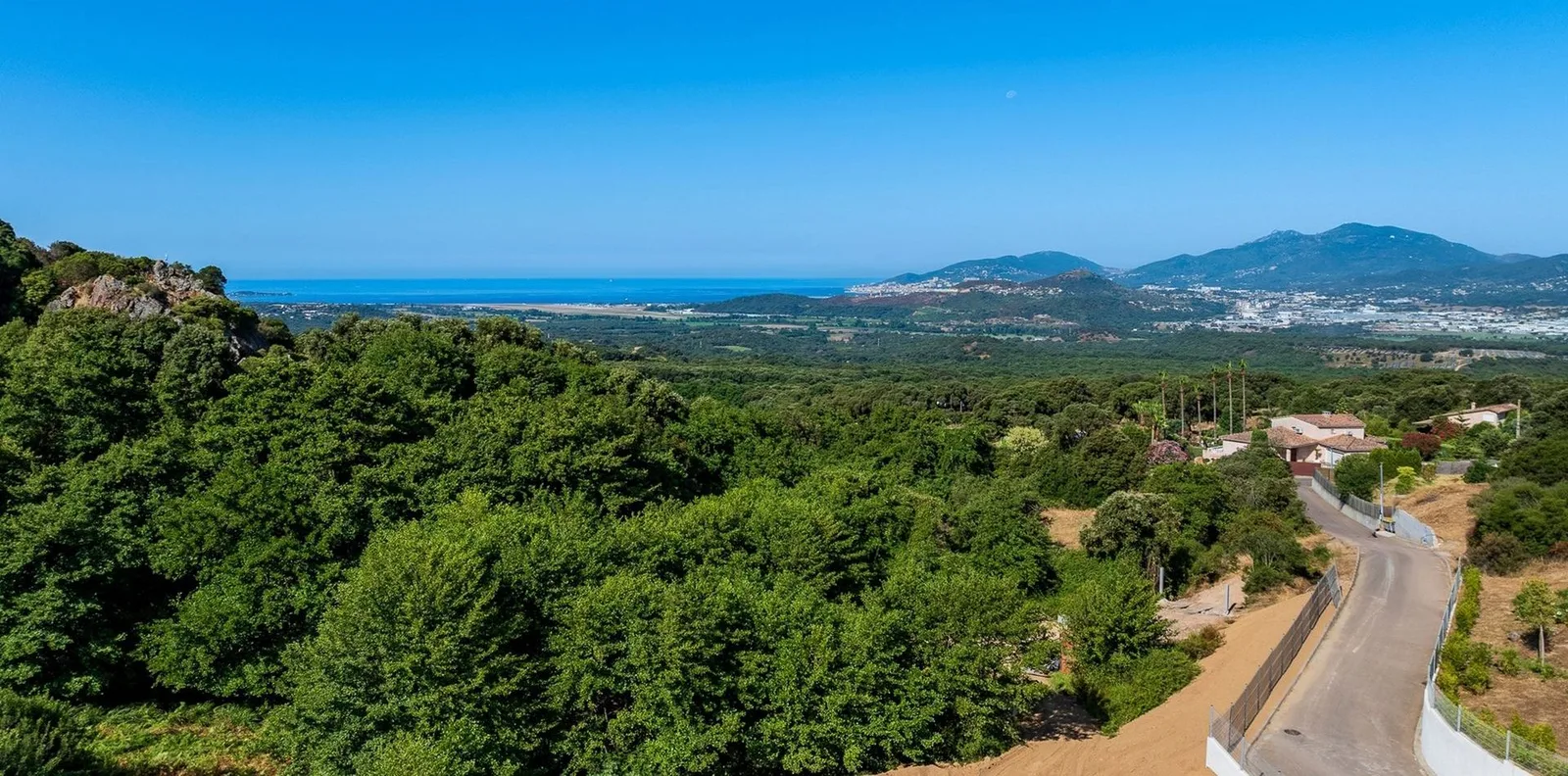 Panorama sur le maquis descendant vers la mer du golfe d'Ajaccio sous un ciel bleu profond