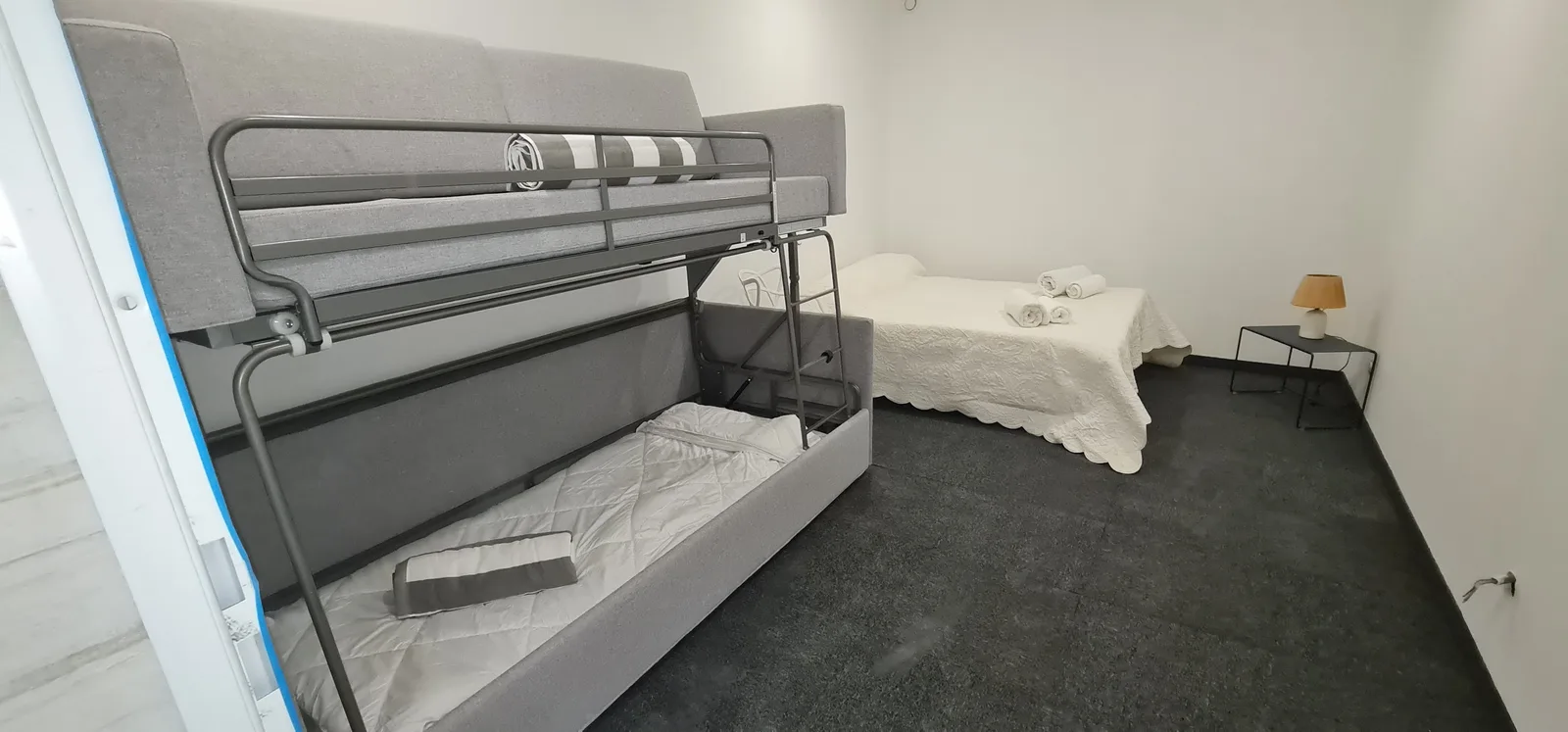 Dortoir clair réunissant un lit superposé et un lit simple habillé de blanc