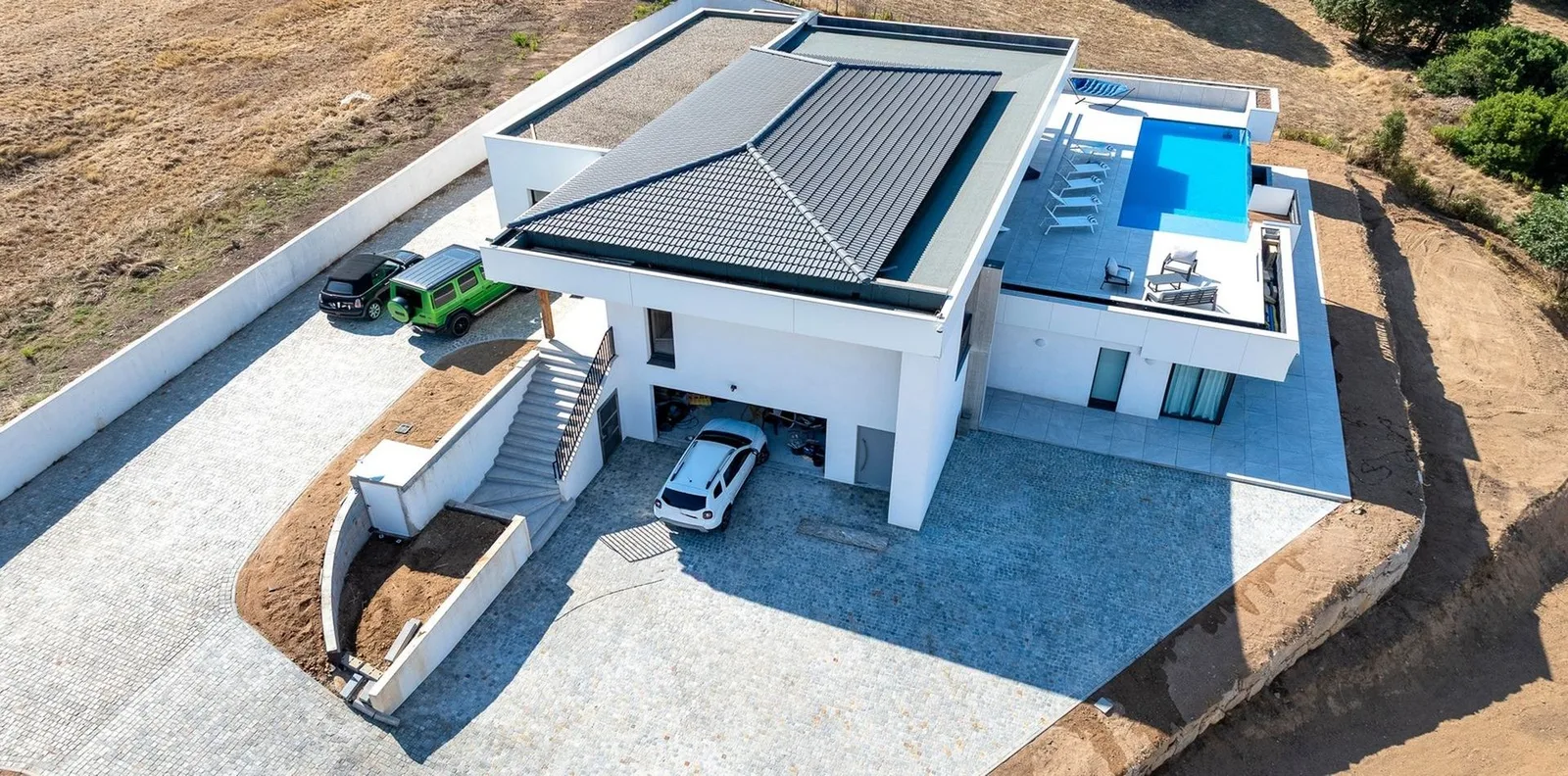 Prise de drone sur le toit incliné, la cour et les voitures garées devant la villa