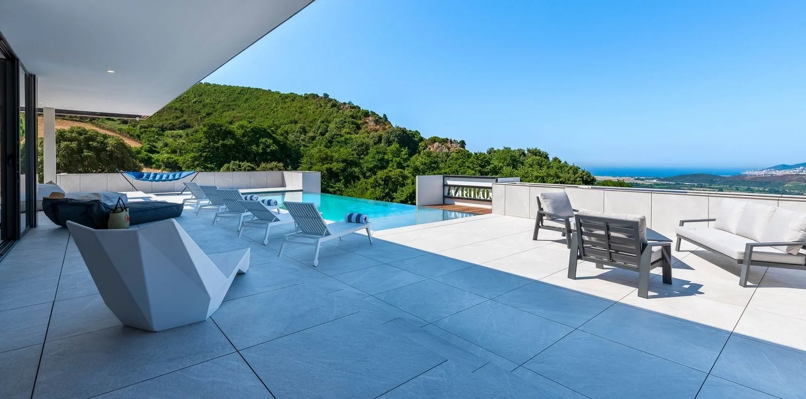 Vaste terrasse avec assises design et bassin ouverts sur la mer au loin