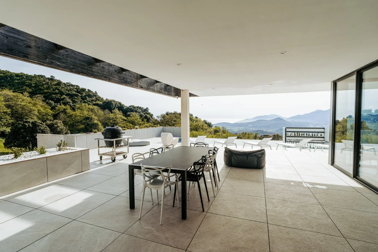 Terrasse couverte avec table à manger, barbecue et panorama sur le golfe