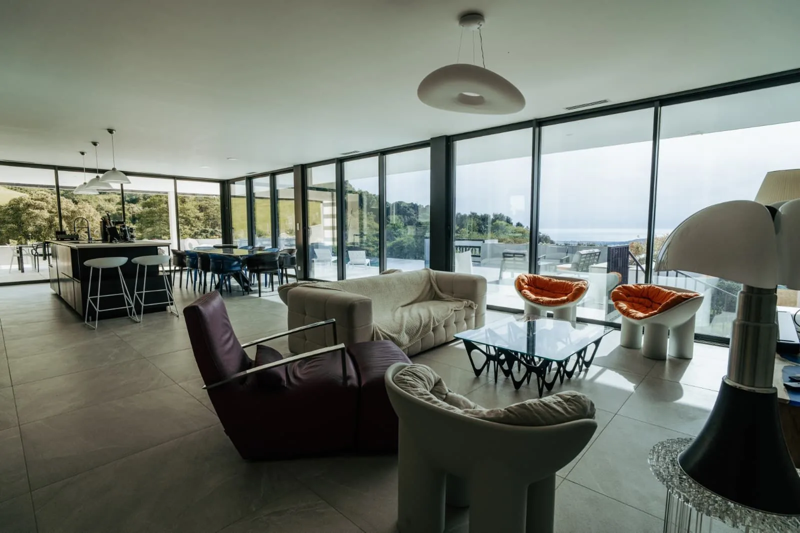 Séjour design aux fauteuils orange et canapés blancs baignés de lumière naturelle